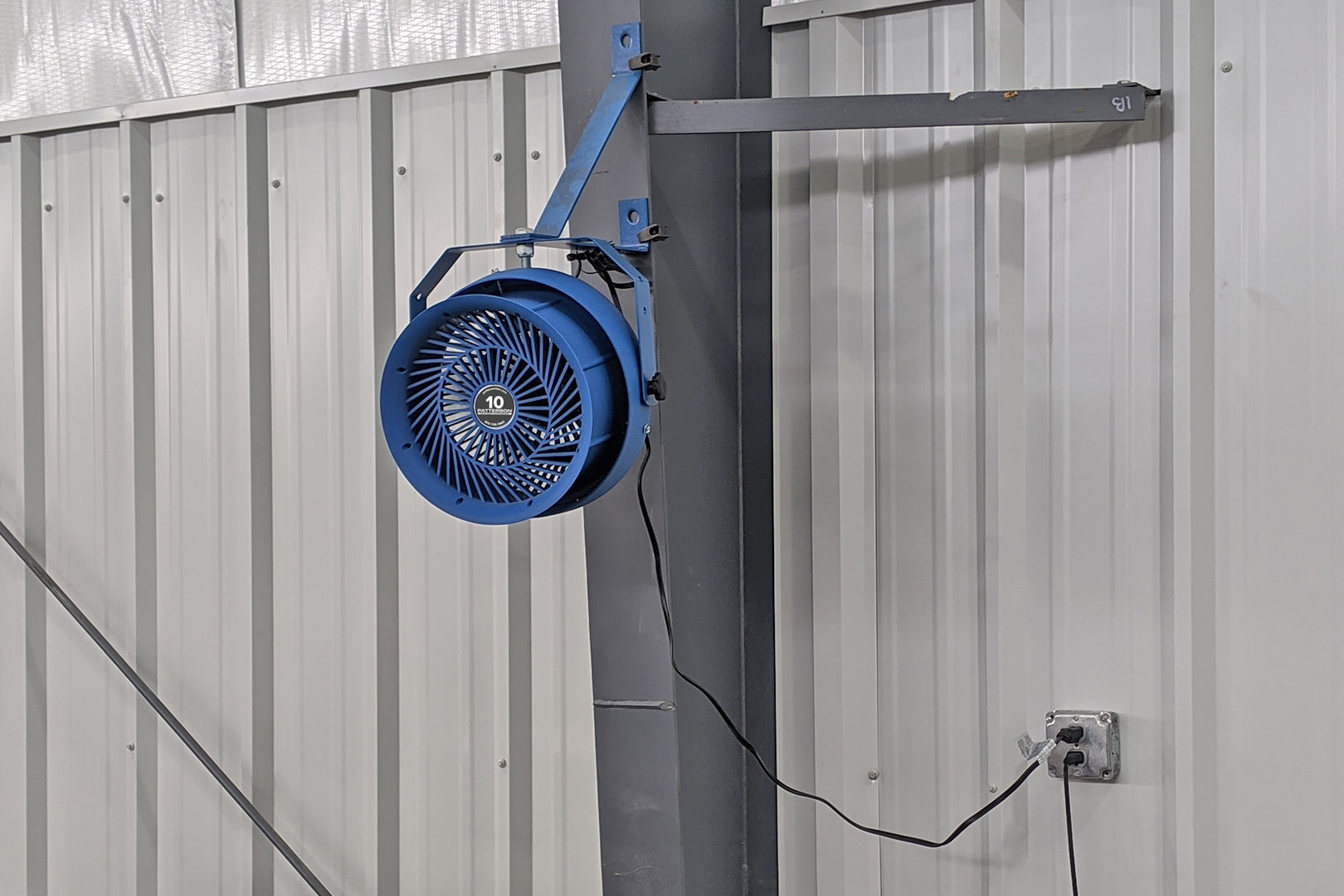 Wall-mounted Patterson 10-inch industrial fan installed on adjustable arm inside a metal building