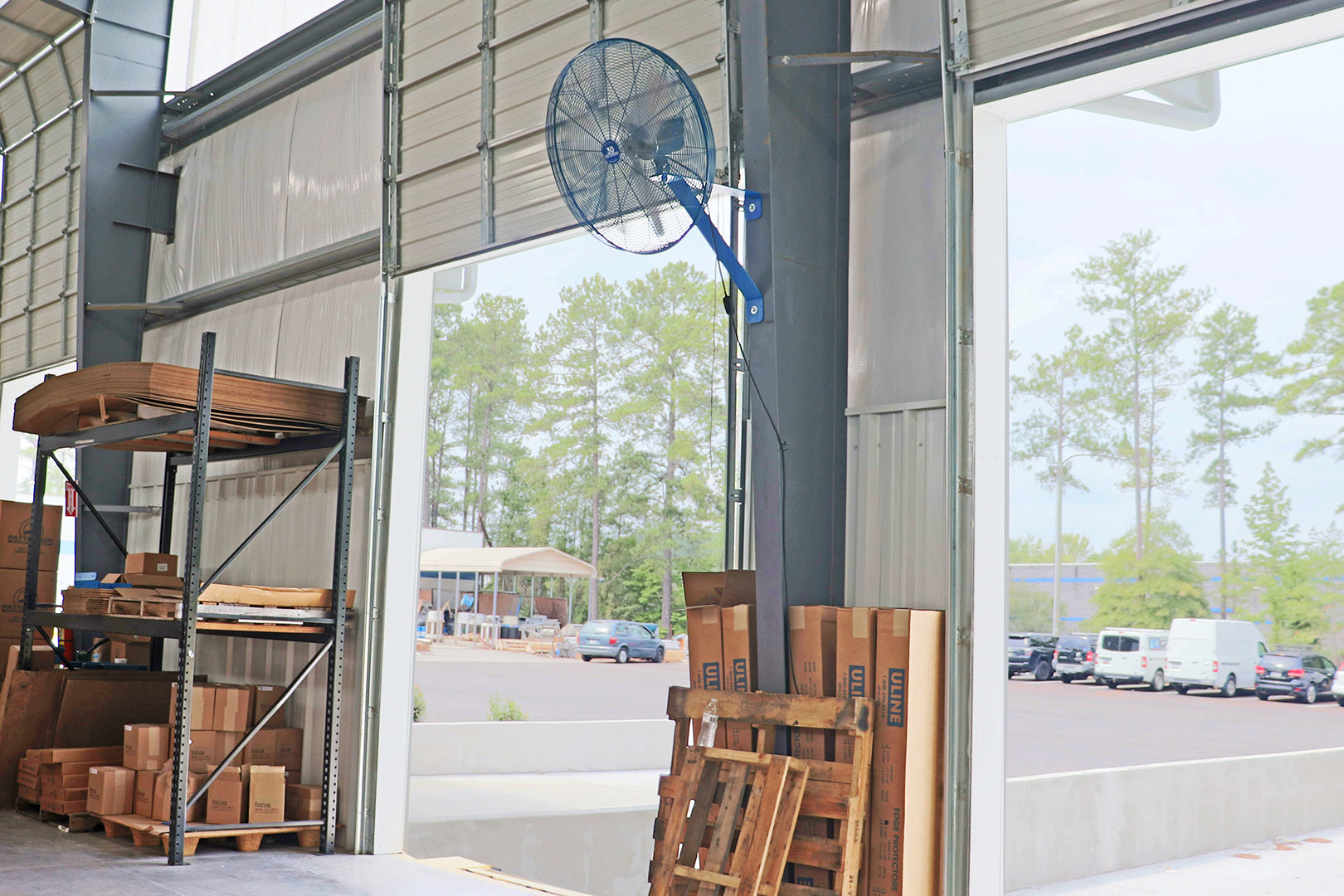 Patterson wall-mounted industrial cage fan installed in an open warehouse doorway for airflow