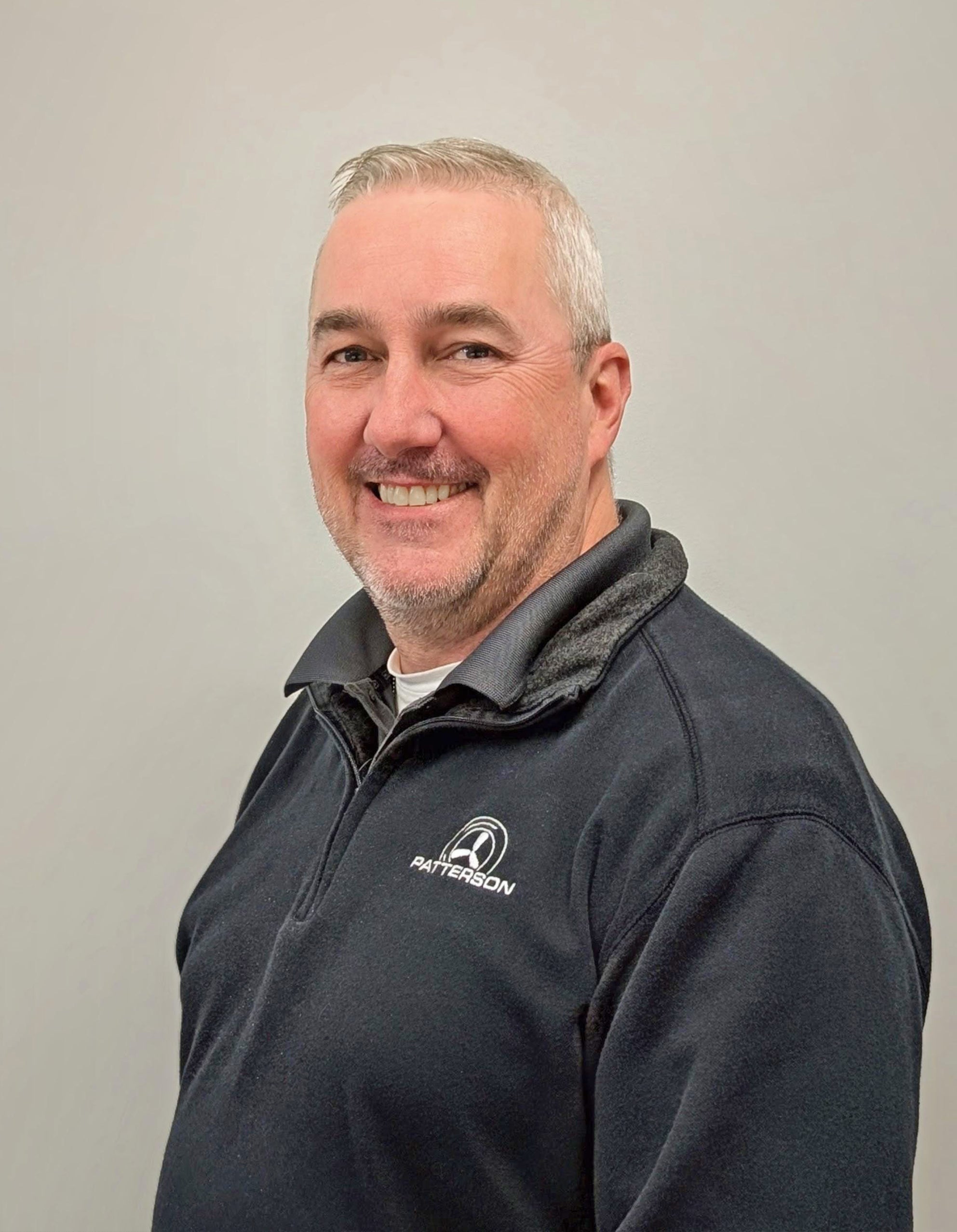 Professional headshot of a man wearing a Patterson-branded quarter-zip pullover