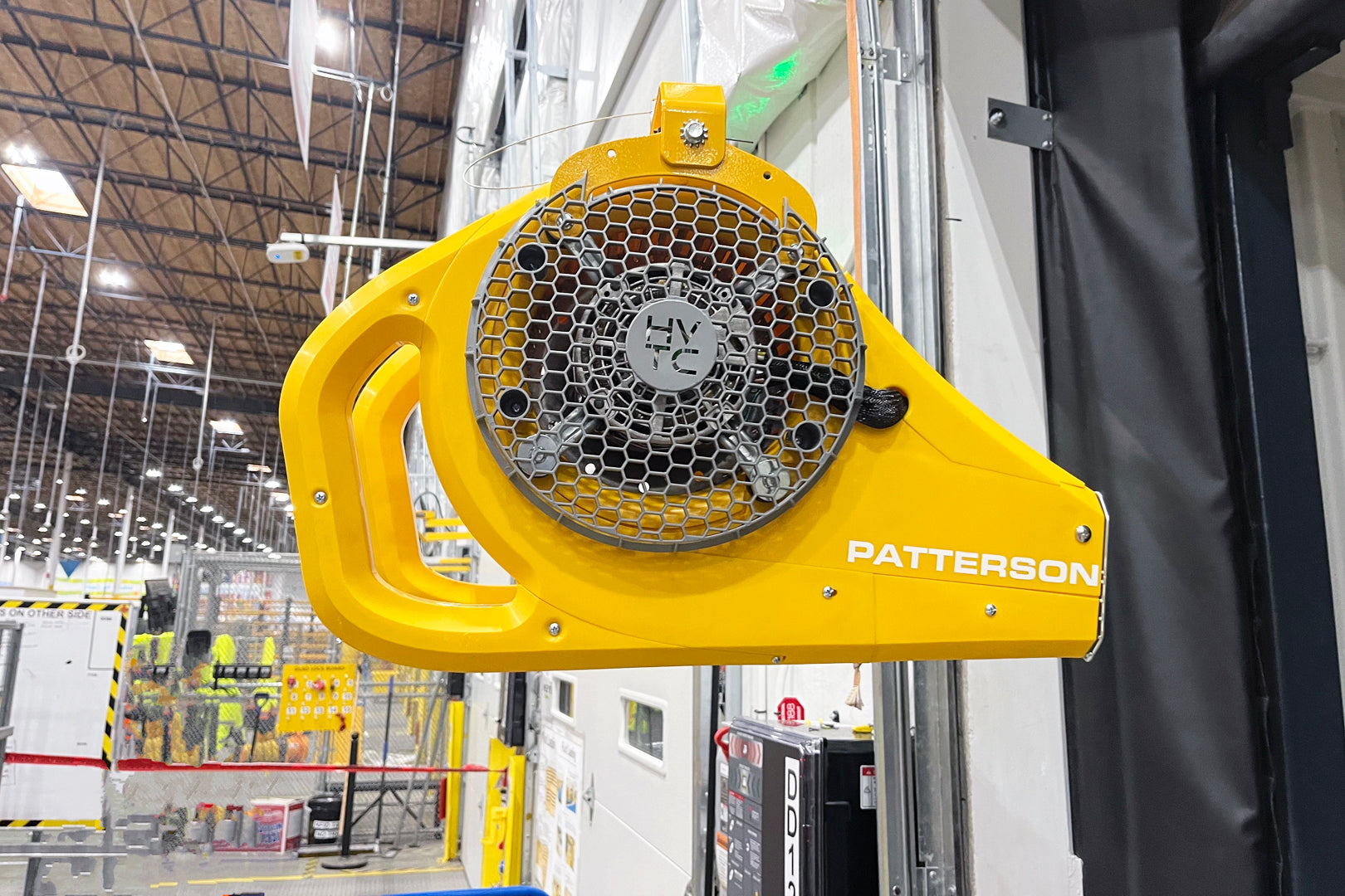 Yellow Patterson industrial fan mounted on a loading dock wall inside a warehouse