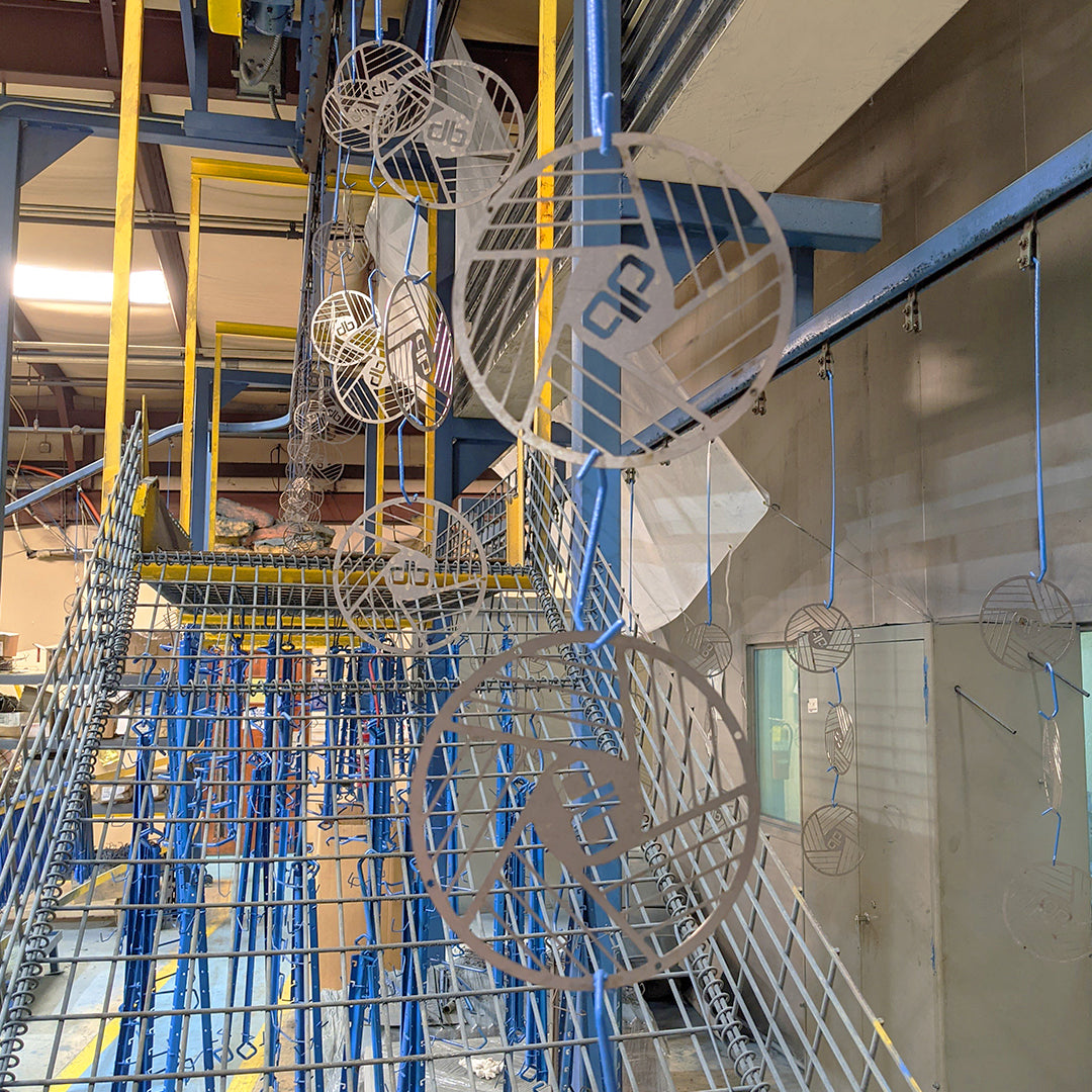 Industrial Patterson fan guards hanging on a paint line inside a warehouse during the fan manufacturing process