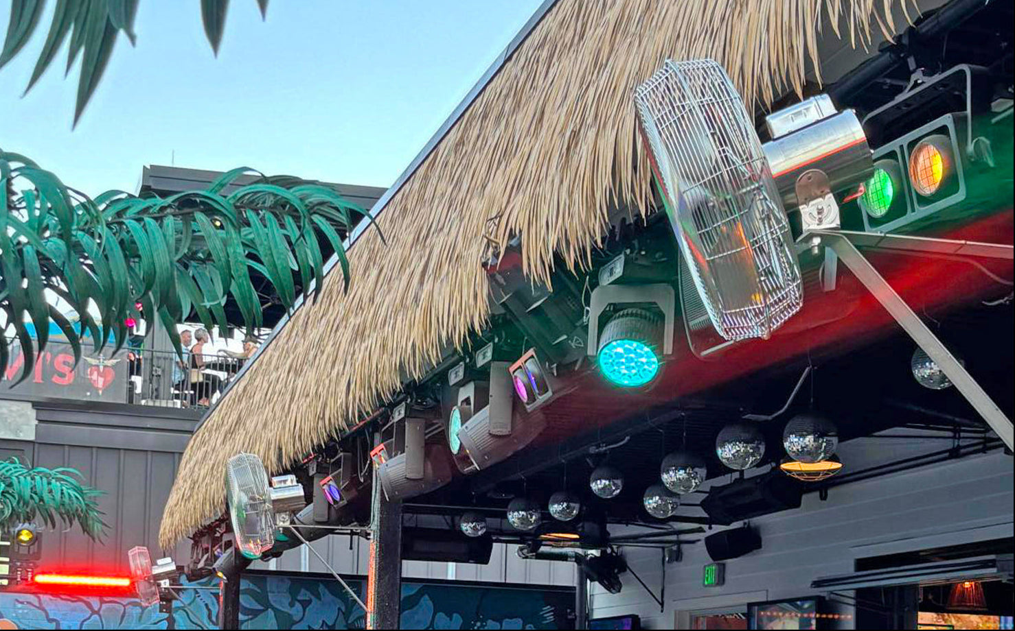 Stainless steel wall mounted cage fan in outdoor bar and music venue.