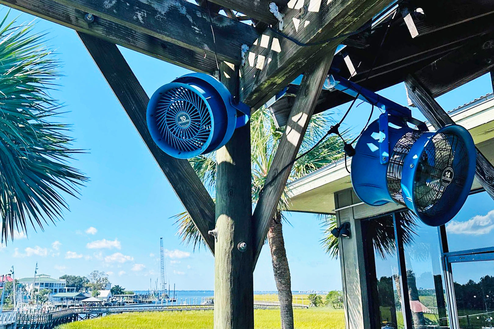 Patterson 10-inch industrial cooling fans mounted outdoors on a wooden pergola at a waterfront area