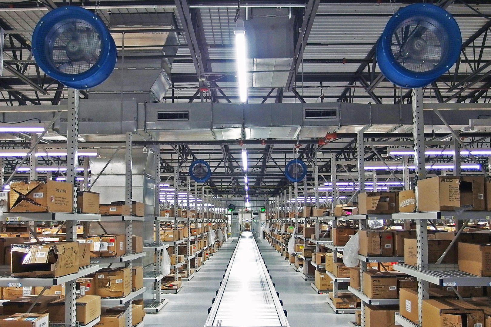Industrial warehouse aisle with Patterson blue circulation fans mounted above storage racks