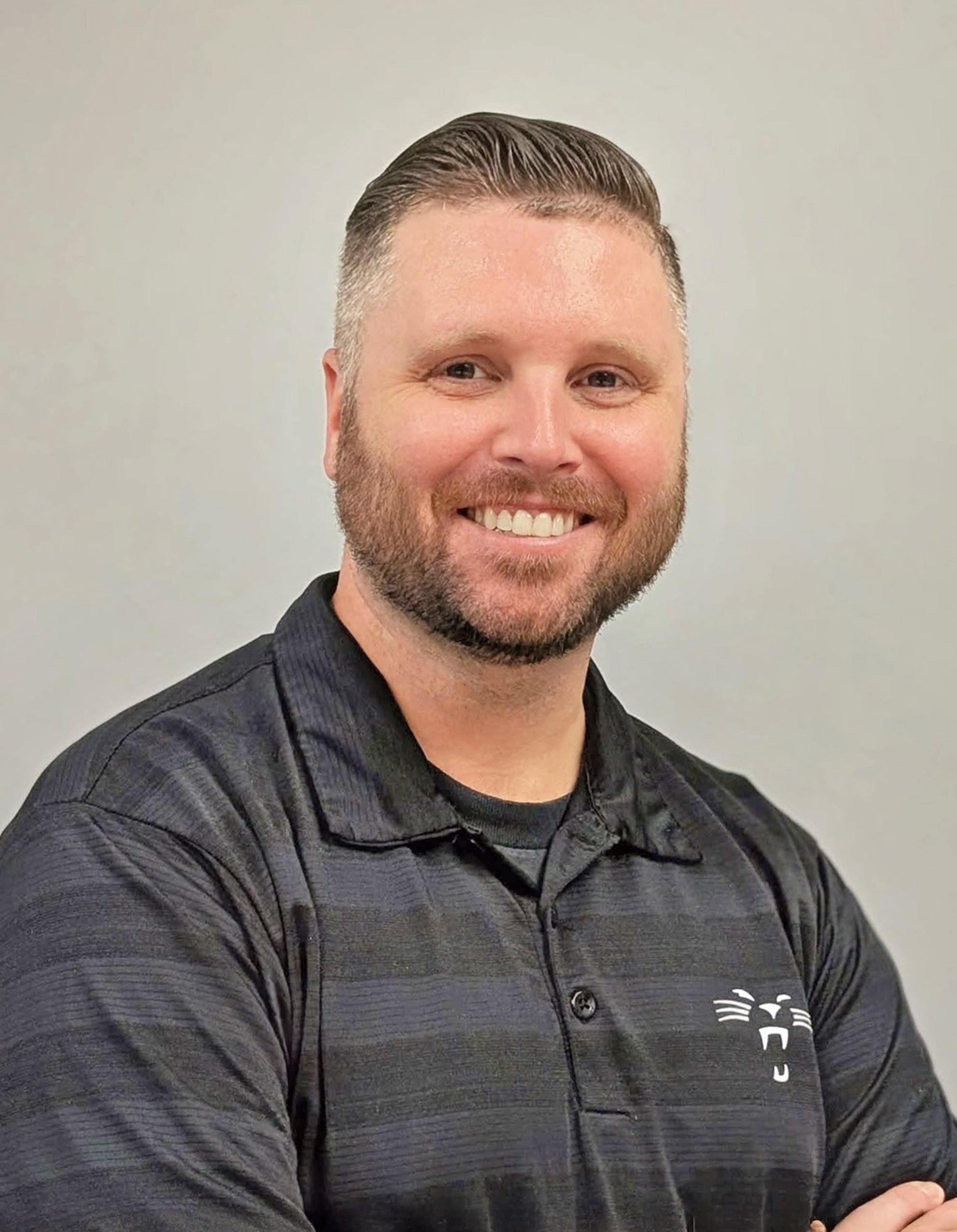 Professional headshot of a smiling man in a dark collared shirt with a company logo