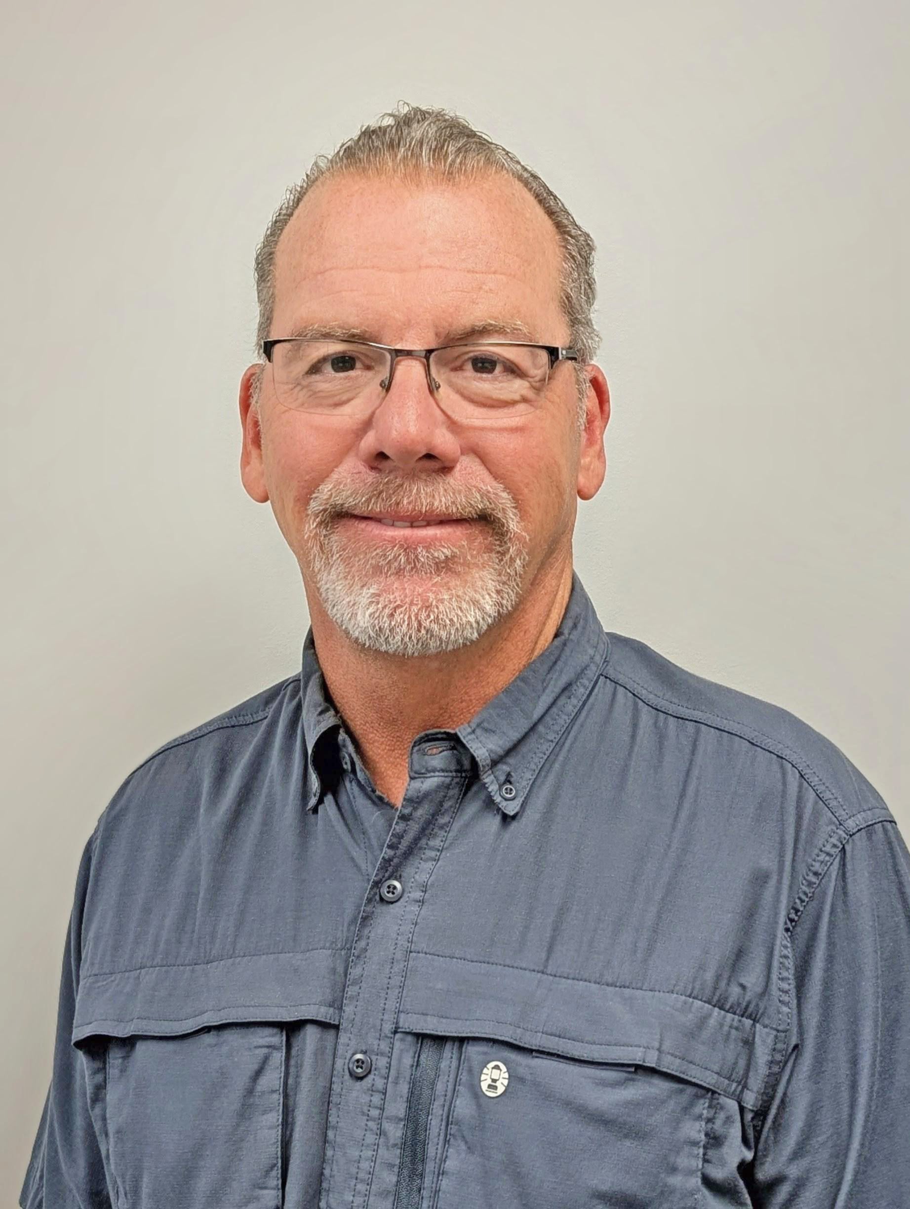 Professional headshot of a smiling man in a dark collared shirt 