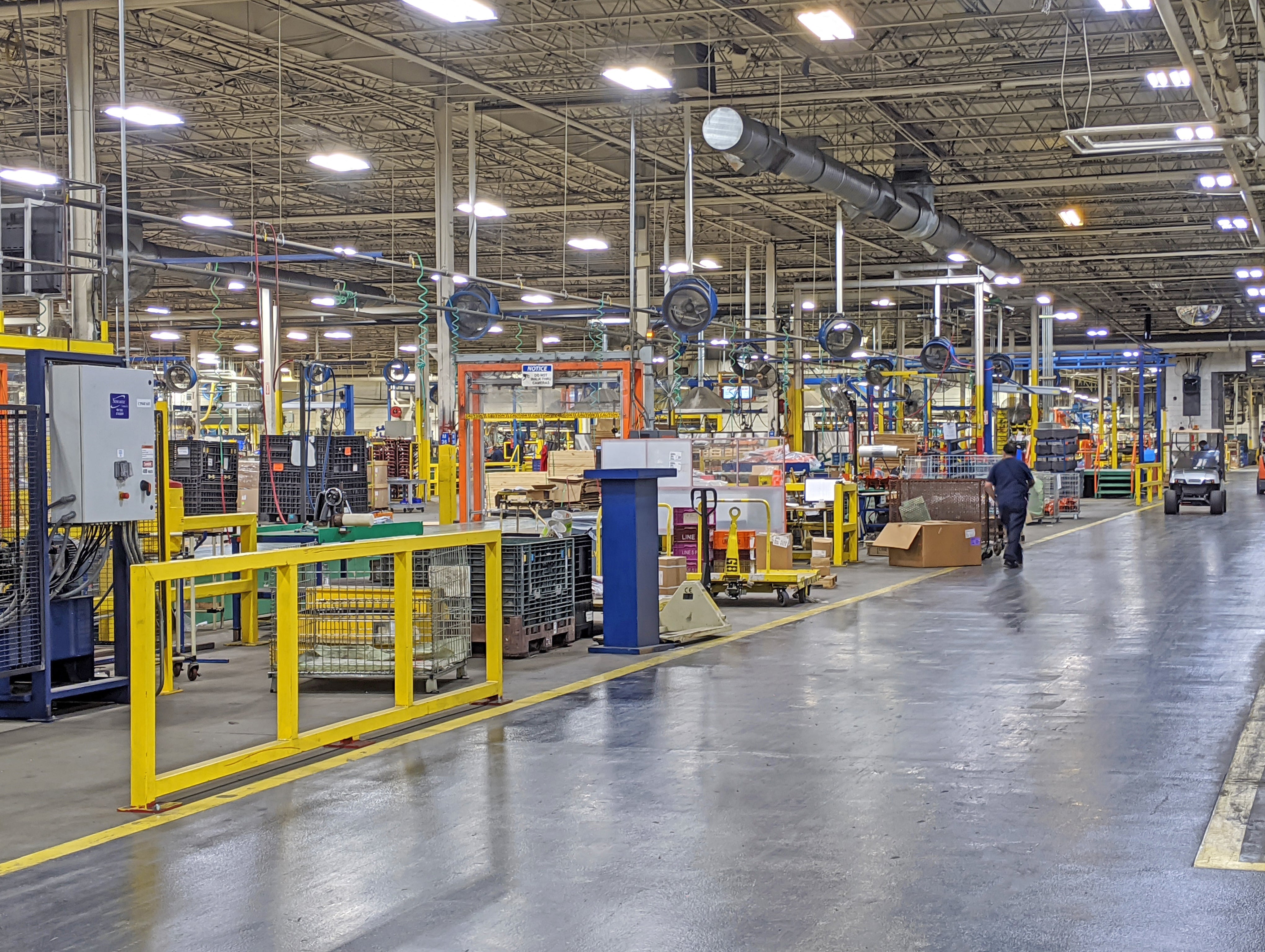 Industrial manufacturing facility featuring multiple large overhead ventilation fans above machinery and workstations