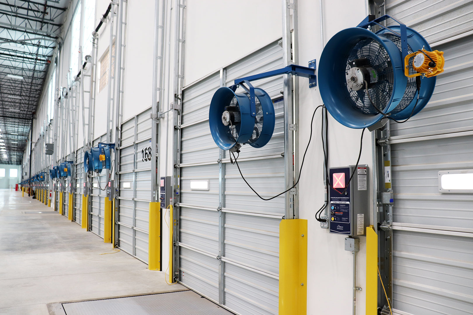 Row of Patterson industrial wall-mounted fans installed along warehouse loading dock doors