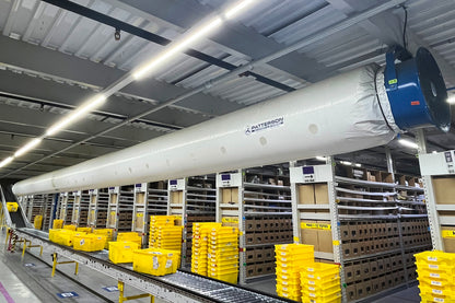 Patterson blower fan with long fabric air distribution tube installed over conveyor lines in a warehouse fulfillment center