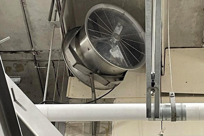 Ceiling-mounted stainless steel industrial fan in a food processing or meat facility