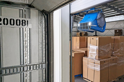 Patterson loading dock door fan mounted above warehouse doorway blowing air into truck trailer with boxed pallets