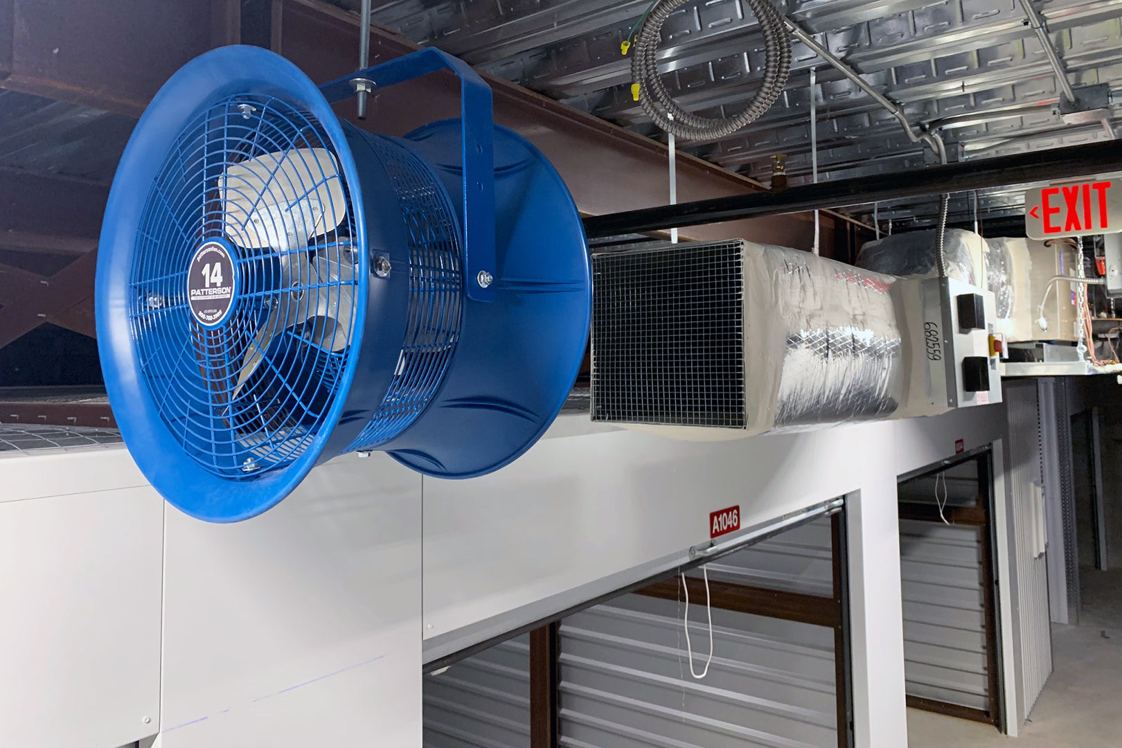 14-inch industrial Patterson wall-mounted blue ventilation fan installed in a storage facility for improved air movement