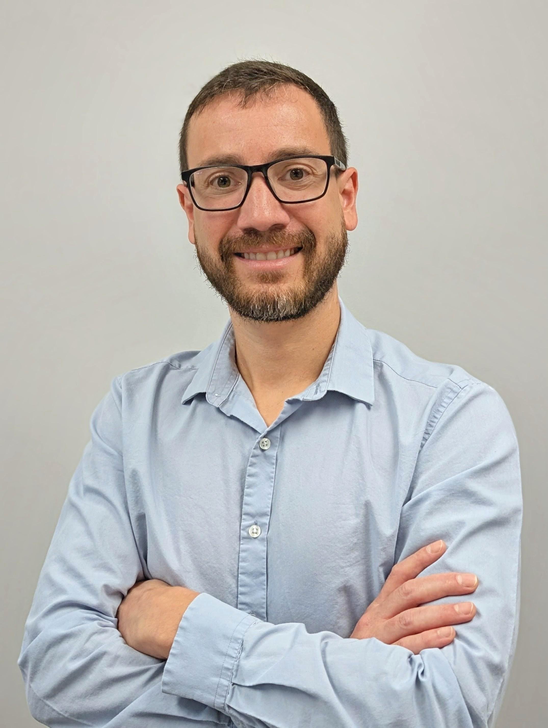 Professional portrait of a man wearing glasses and blue collared shirt
