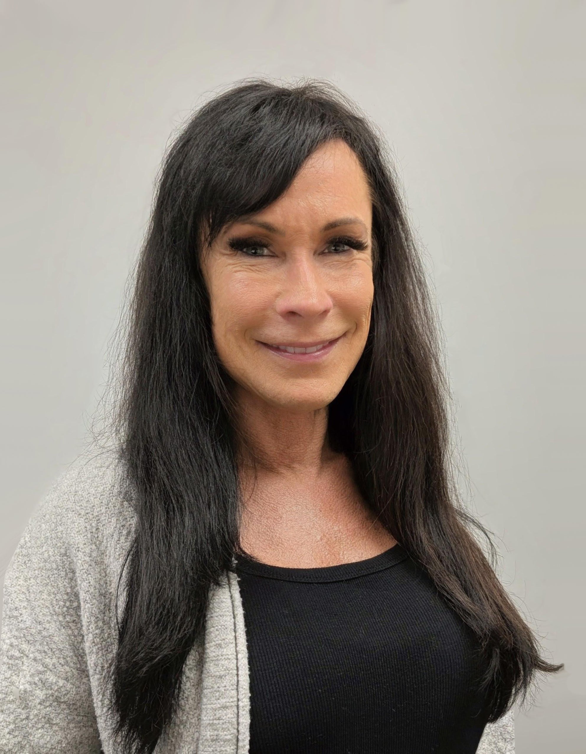 Professional headshot of a woman wearing a black top and light cardigan