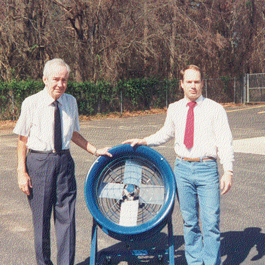 Two men standing beside a Patterson industrial fan, representing the company's father-and-son business roots