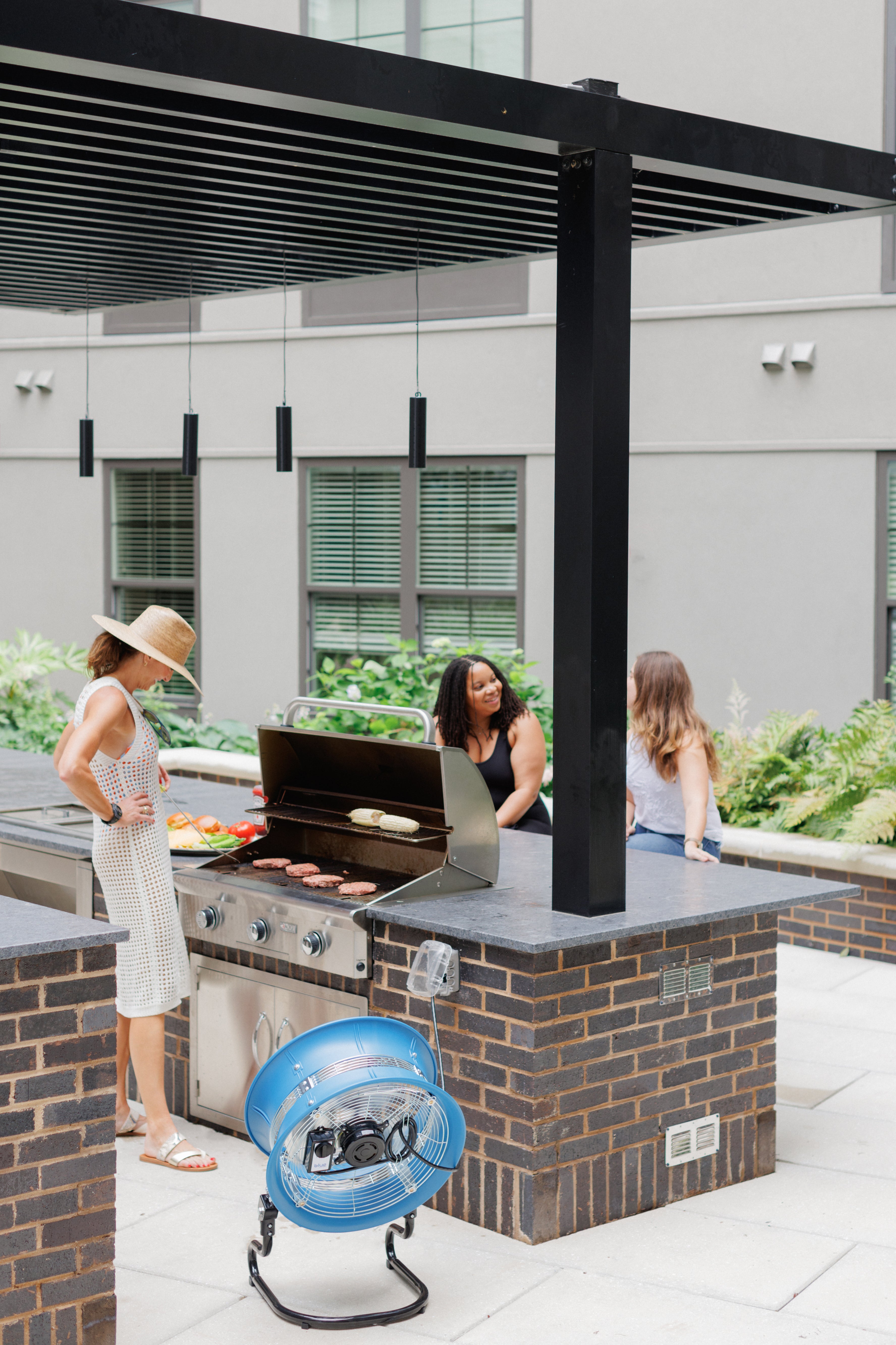 Portable blue floor fan placed near an outdoor grill station during a cookout
