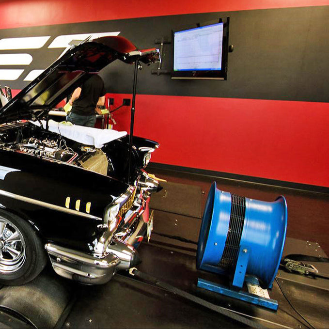 Blue industrial fan positioned in front of a classic car during engine testing in a dyno room