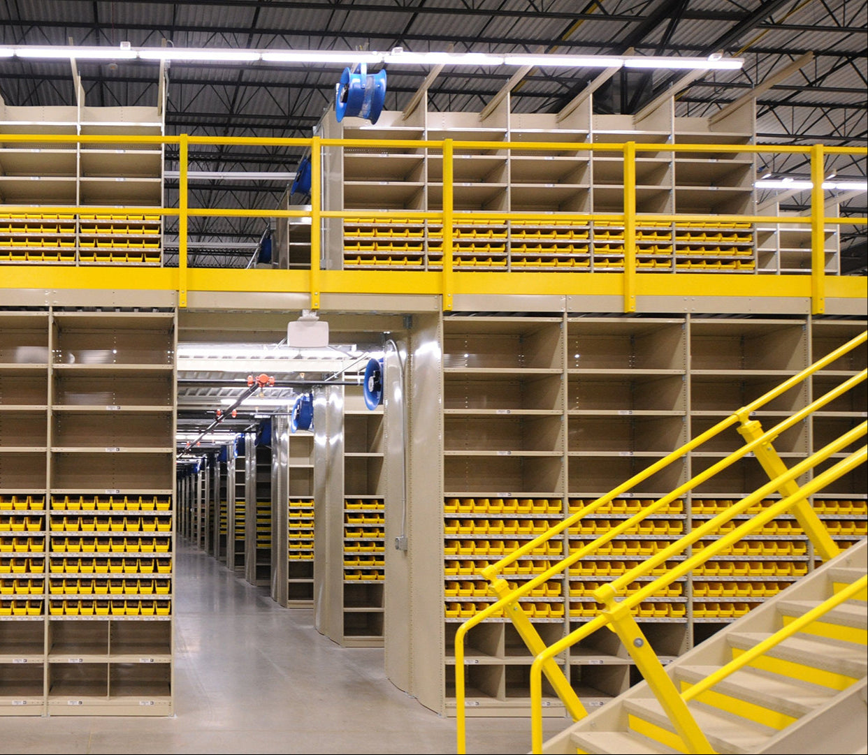 Warehouse shelving system with yellow railings and mounted blue industrial fans for ventilation