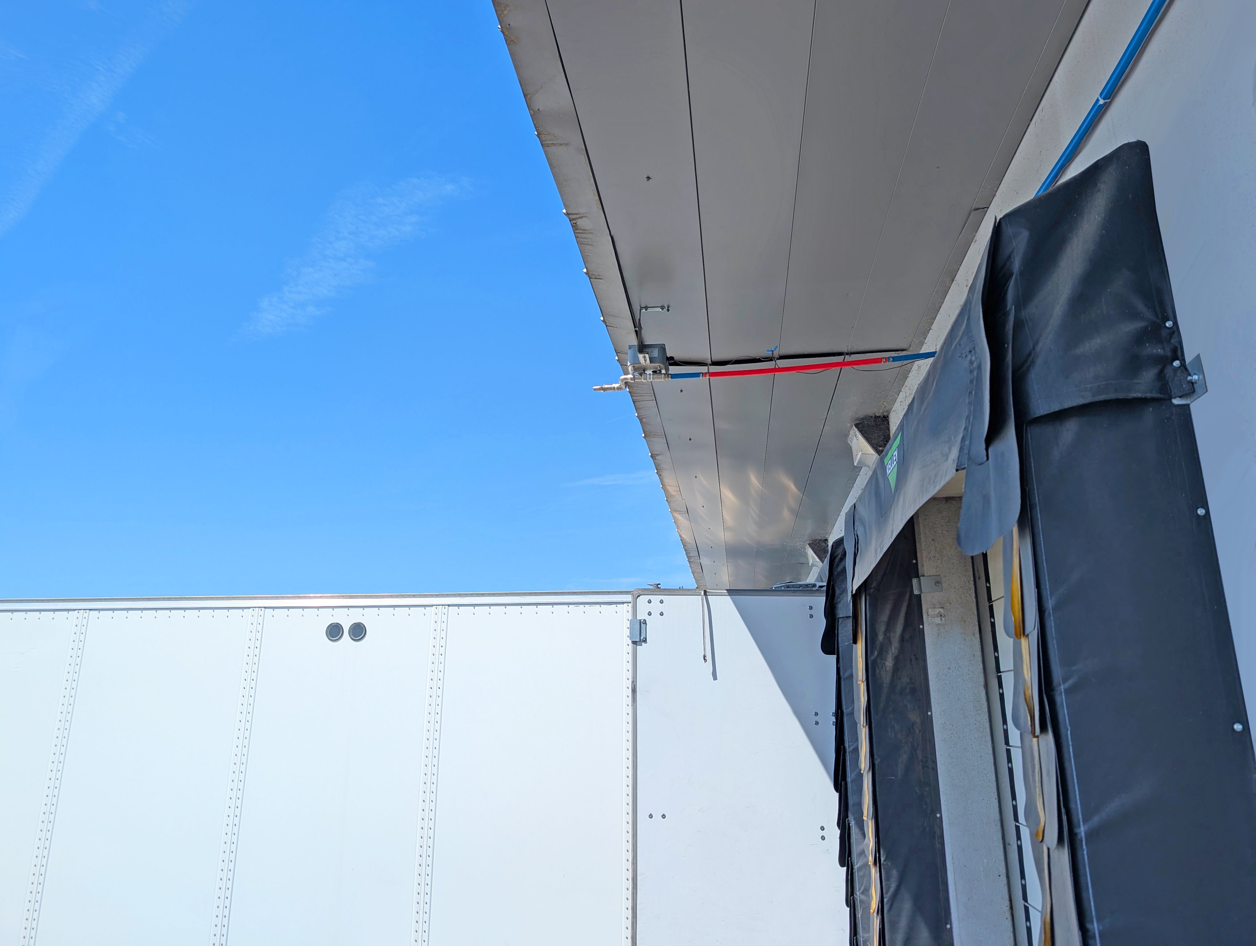 Mounted overhead evaporative truck cooler installed above a truck dock canopy