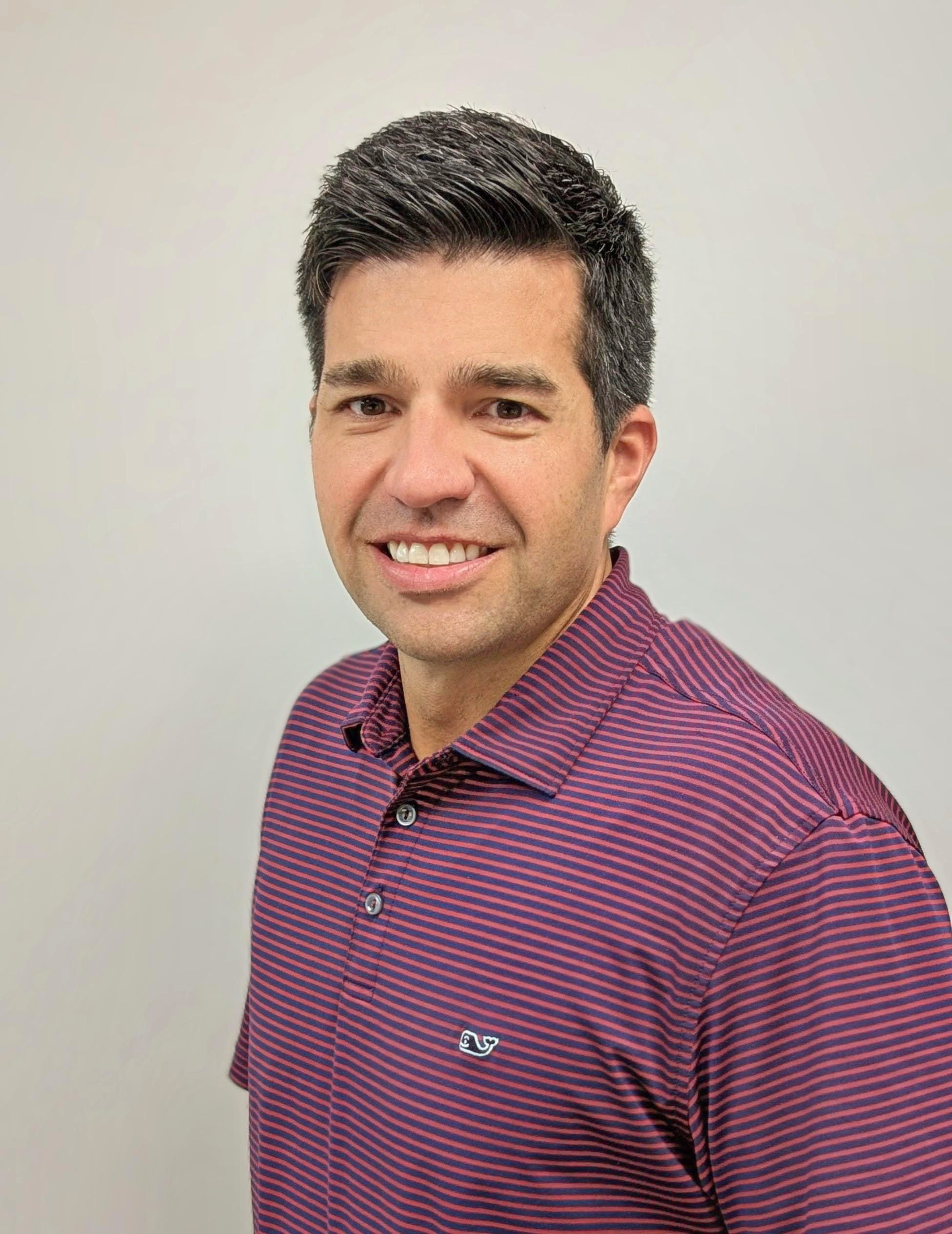 Professional portrait of a man wearing a maroon striped polo shirt