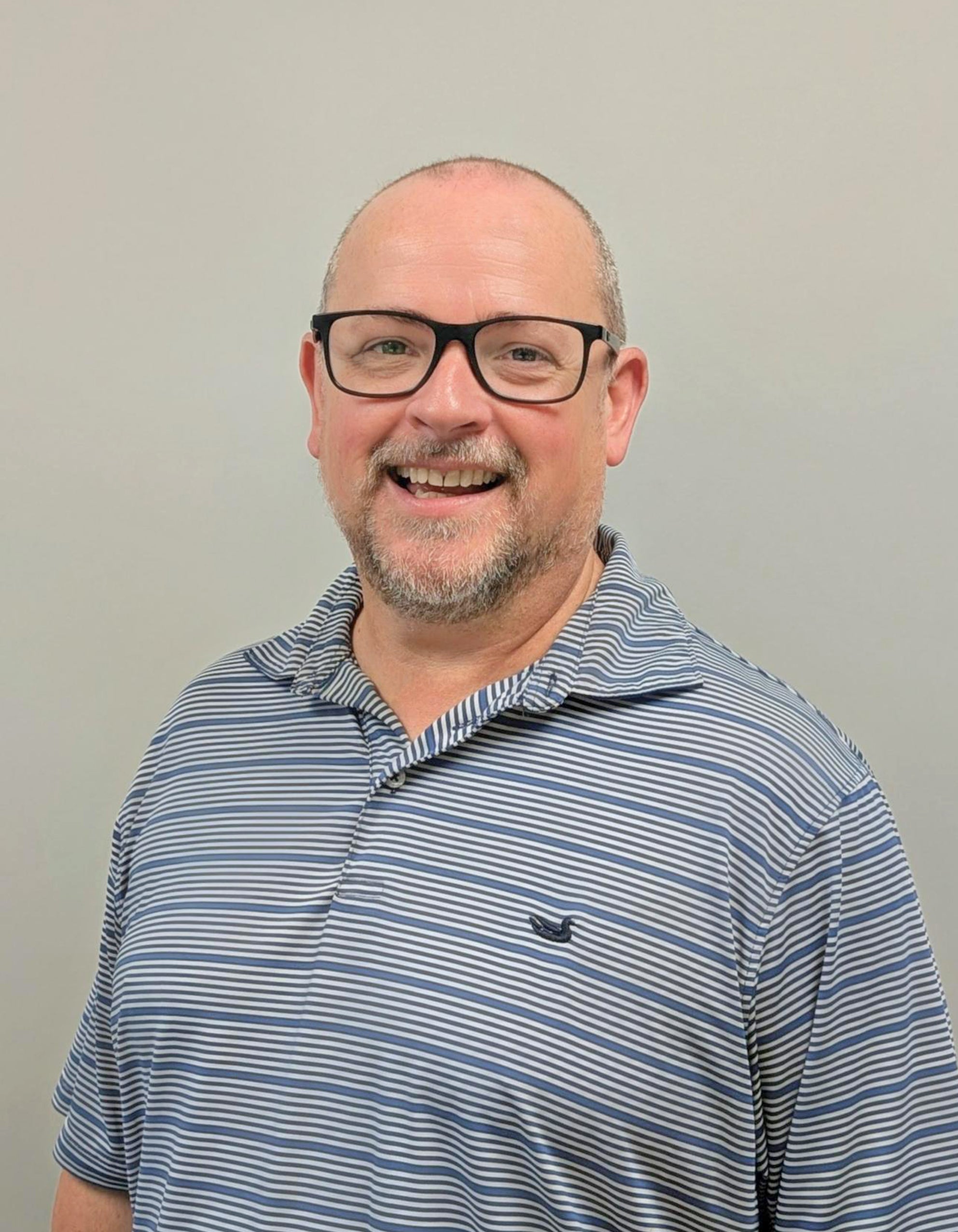Professional portrait of a man wearing glasses and a striped polo