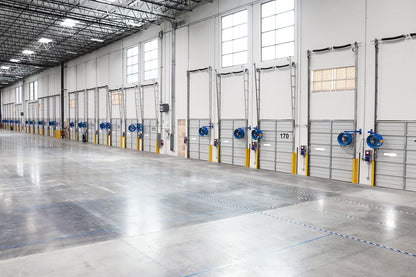Warehouse loading dock doors equipment with blue Patterson industrial wall-mounted fans