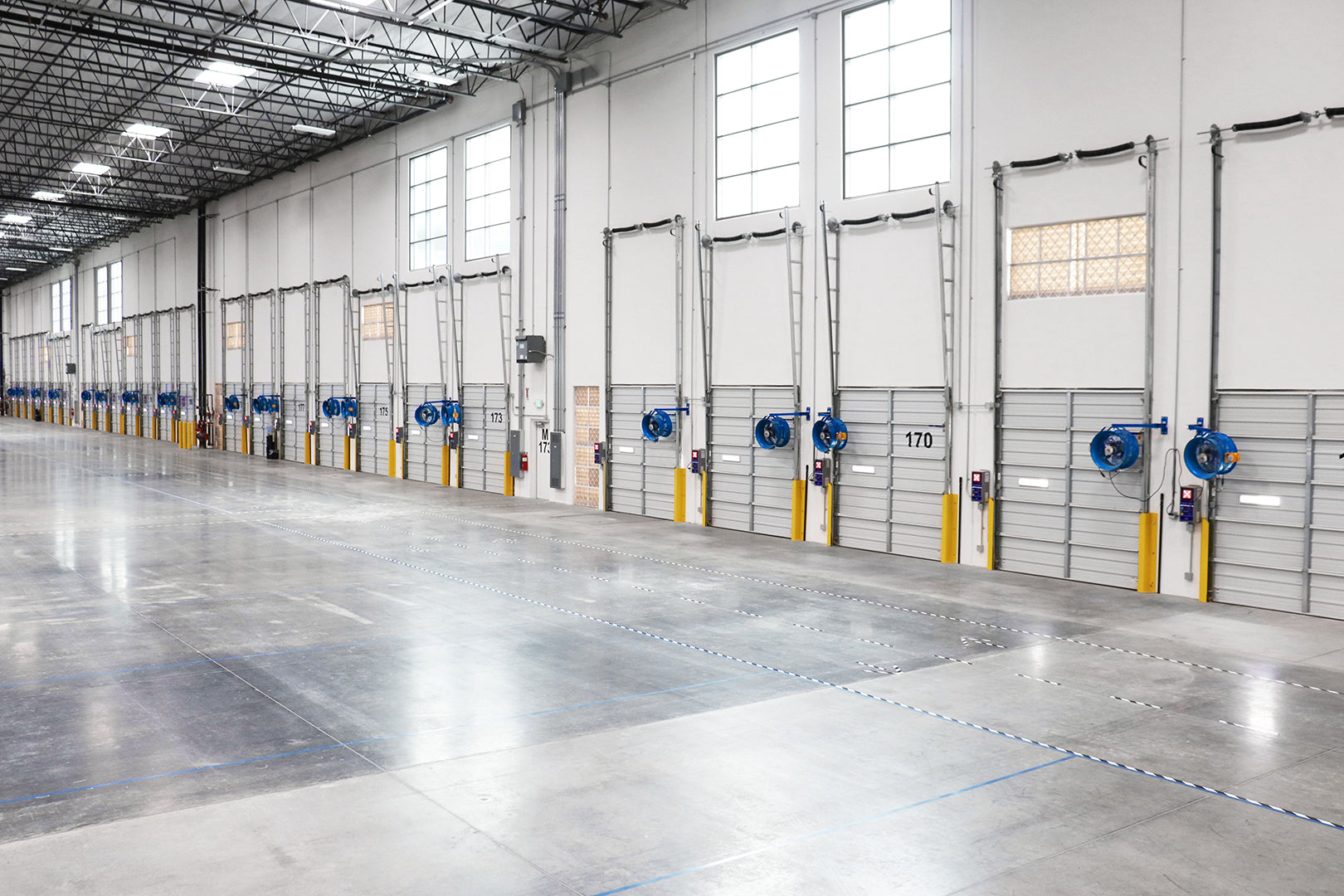 Warehouse loading dock doors equipment with blue Patterson industrial wall-mounted fans