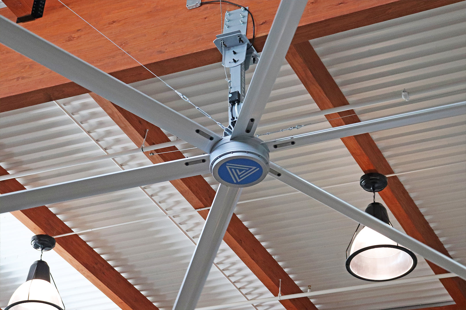 Large V-Series Patterson HVLS Fan installed in a commercial space with exposed wood beams and pendant lighting