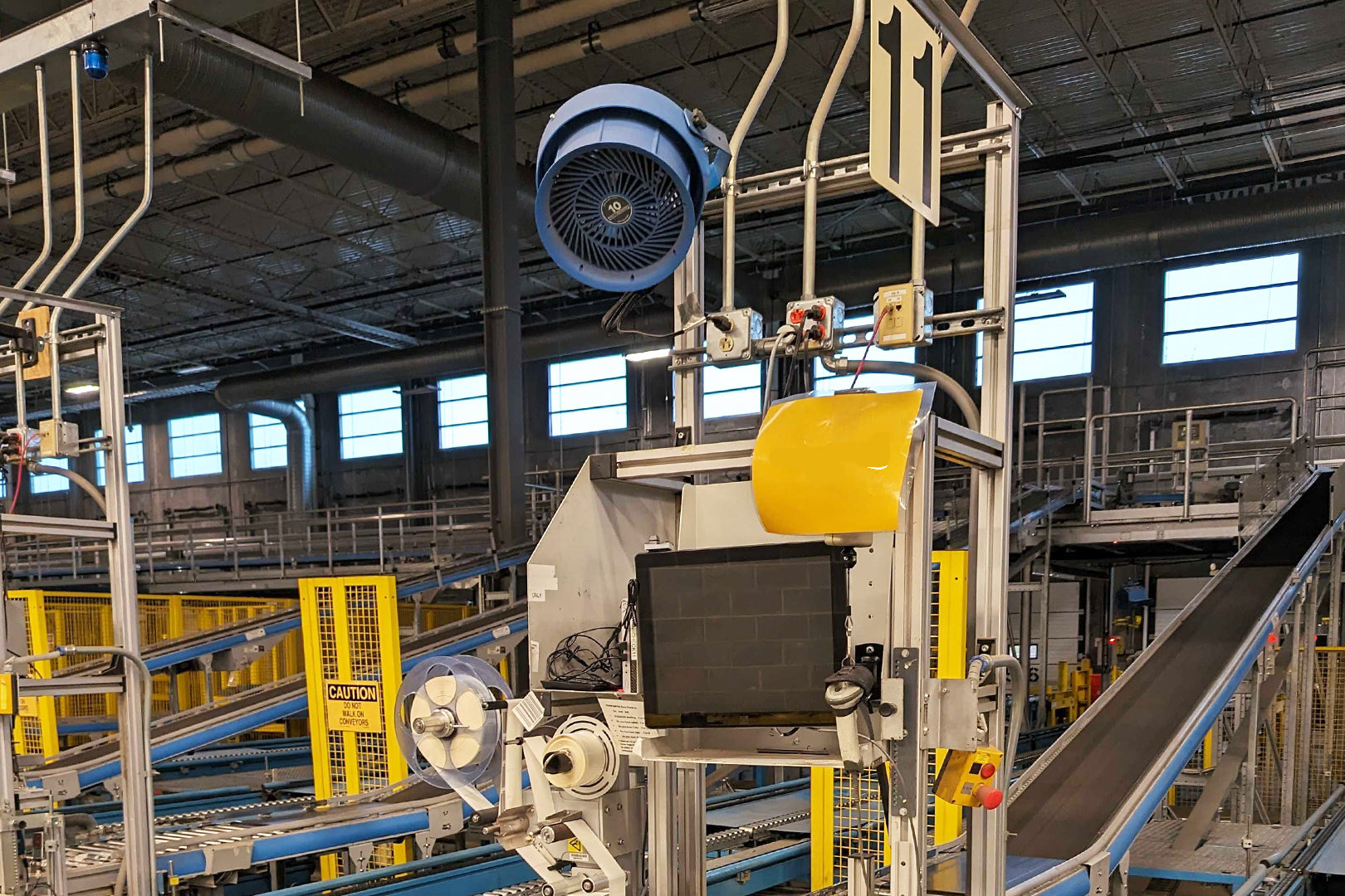 Patterson 10-inch industrial fan mounted above a conveyor system in a warehouse facility