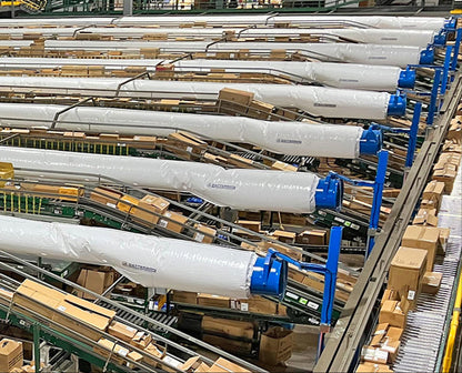 Multiple Patterson blower fans with long fabric duct socks installed above conveyor lines in a distribution center
