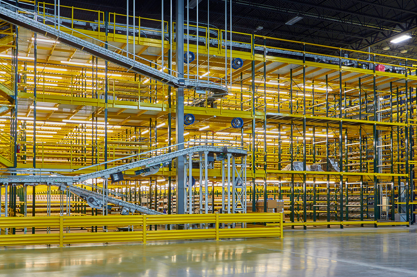 Large multi-level warehouse racking system with integrated conveyor lines and industrial circulation fans