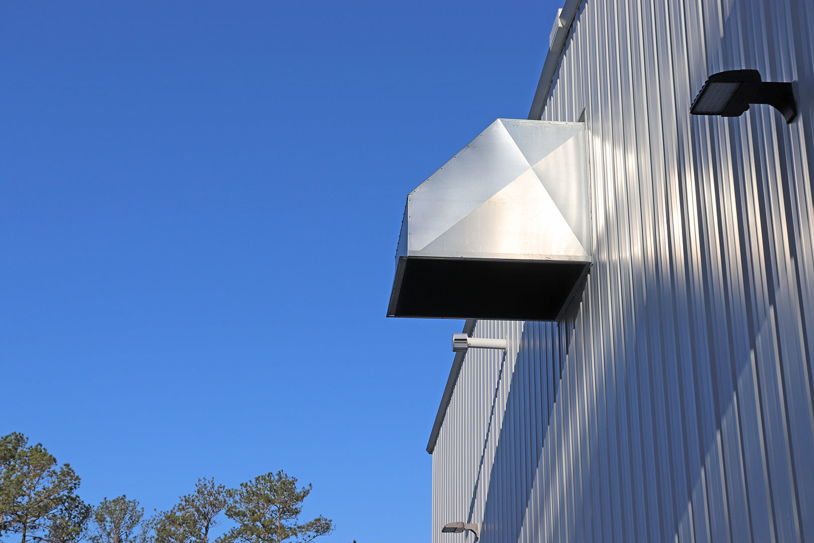 Exterior wall-mounted industrial exhaust hood on a metal building