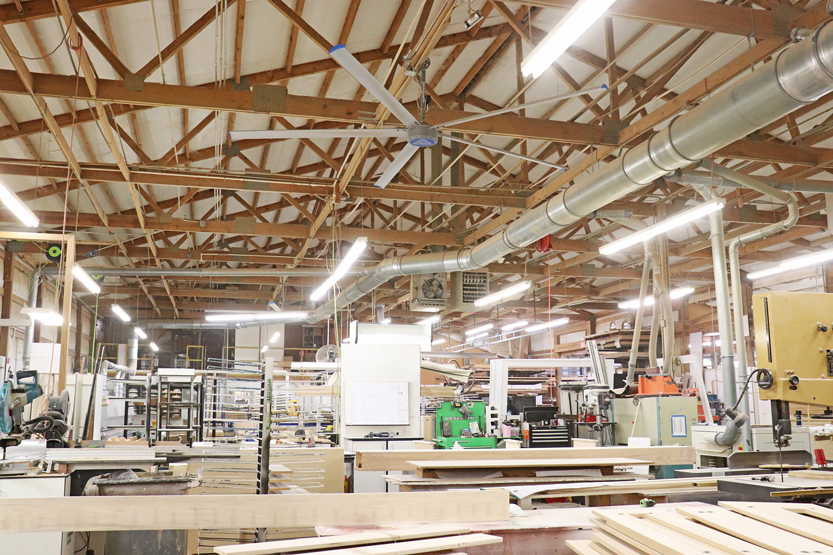 Large HVLS ceiling fan providing airflow in a busy woodworking shop with equipment